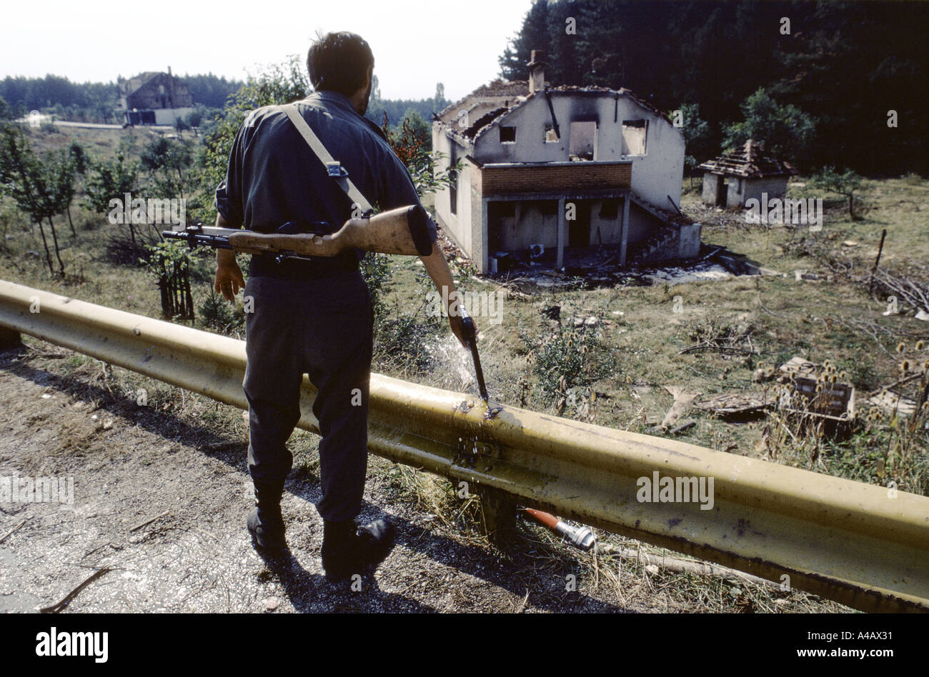 Un soldato serbo in guardia dal ciglio della strada si affaccia su case bruciate in pulizia etnica di serbi di Sarajevo controllata 1992 Foto Stock