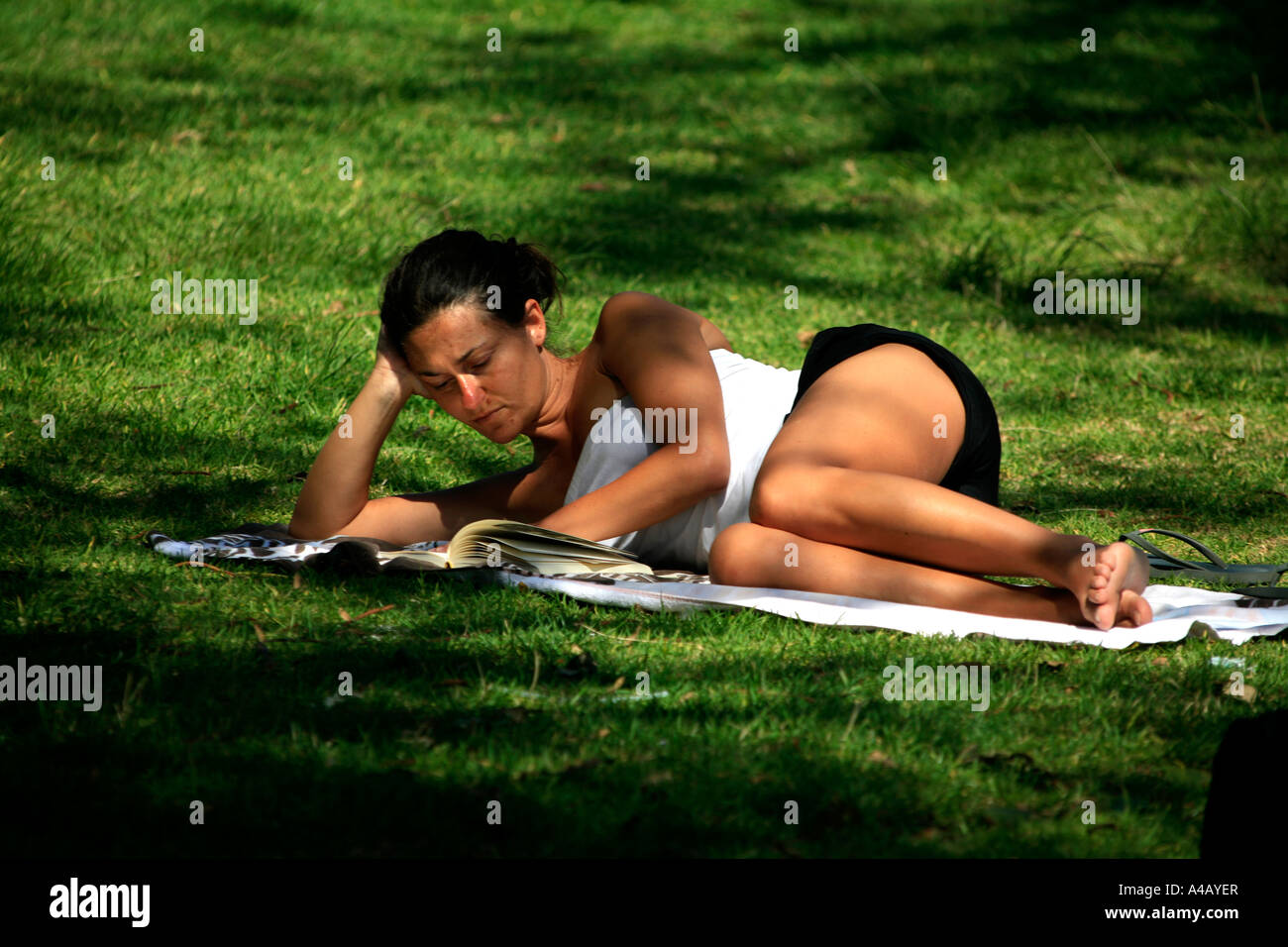 Una ragazza legge su un sonnolento pomeriggio a Manly Australia Foto Stock