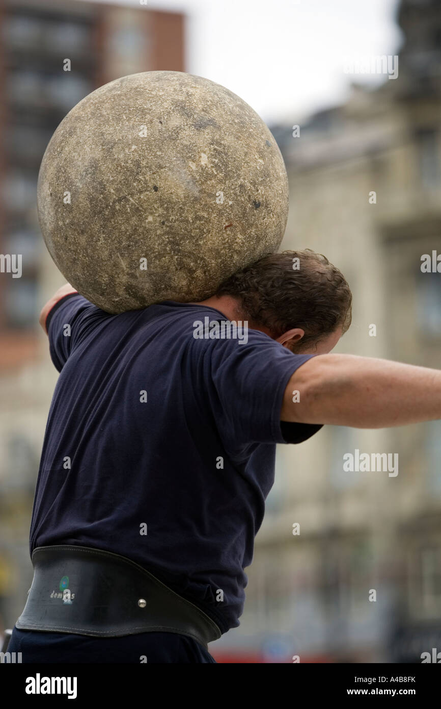 Harrijasotzaileak (pietra sollevamento) concorrente portando la sfera di granito su spalle, basco uomo forte giochi, Bilbao, Paese Basco Foto Stock