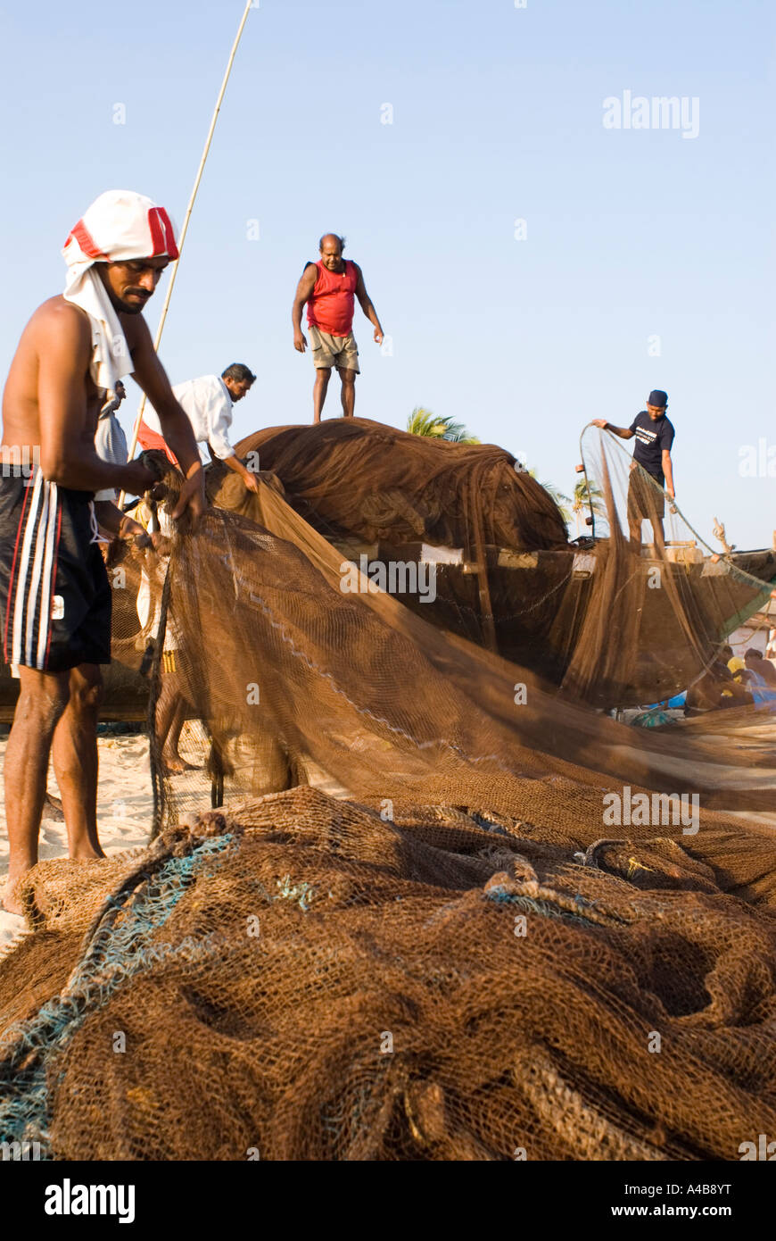 Immagine di stock di Goa pescatori caricamento di reti da pesca su barche da pesca sulla spiaggia Benaulim in Goa in India Foto Stock
