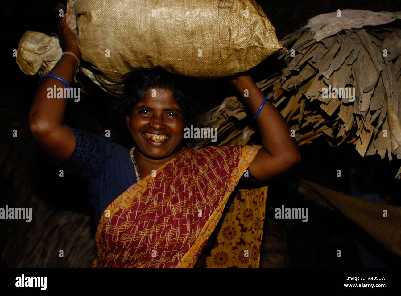 Immagine di stock di indiani tribali dalit Donna sorridente e portante un sacco di cibo sul suo capo Foto Stock Immagine di stock di indiani tribali dalit Donna sorridente e portante un sacco di cibo sul suo capo Foto Stock