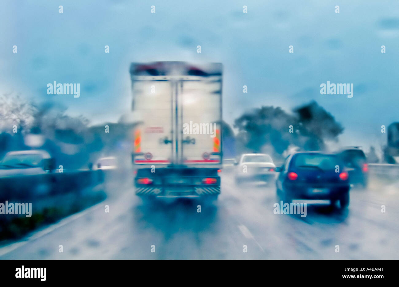 Pontina strada nazionale, in Italia, durante un pesante giornata piovosa, con camion e automobili prese da dietro Foto Stock