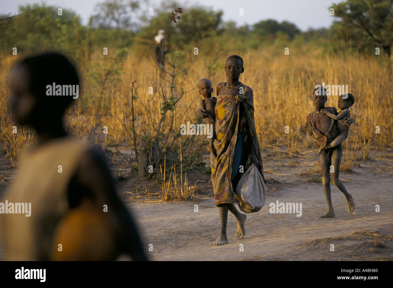 Il sud Sudan ageip village malnutriti madre di famiglia che porta i bambini a camminare sulla strada Foto Stock