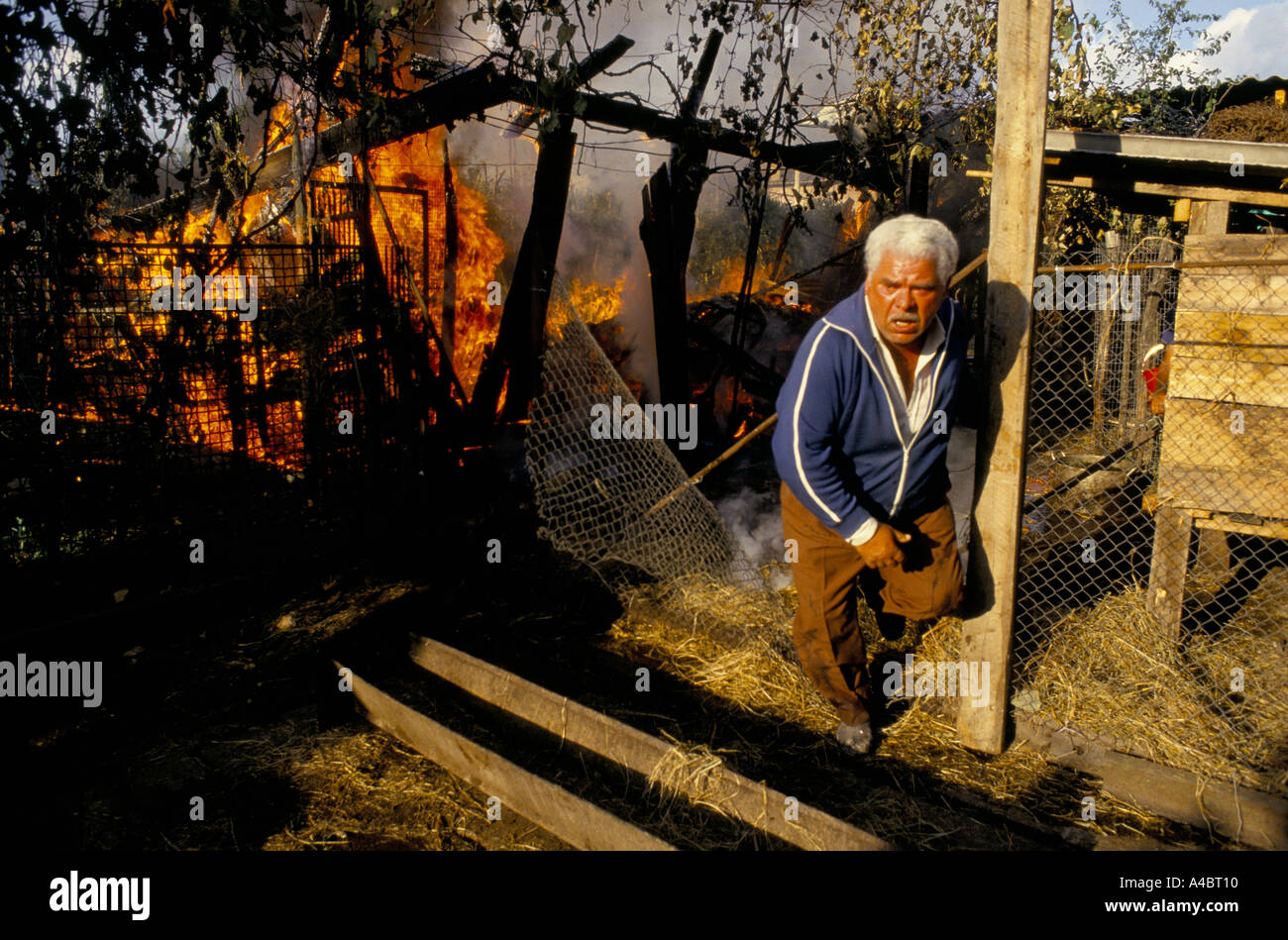 OCHAMCHIRE, GEORGIA, 28 settembre 1993:un uomo tenta di spegnere le fiamme dopo la sua casa è stata colpita in un razzo Abkhazian attaccare il giorno dopo la caduta di Sukhumi a Abkhazian le forze separatiste. Foto Stock