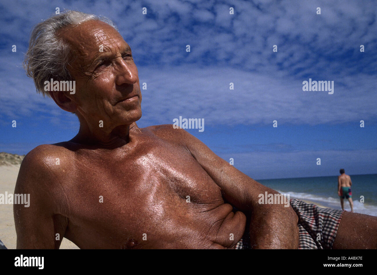 Il Portogallo. Alexander Jakober; suntanned dai capelli grigi uomo anziano sdraiata su una spiaggia assolata. Foto Stock