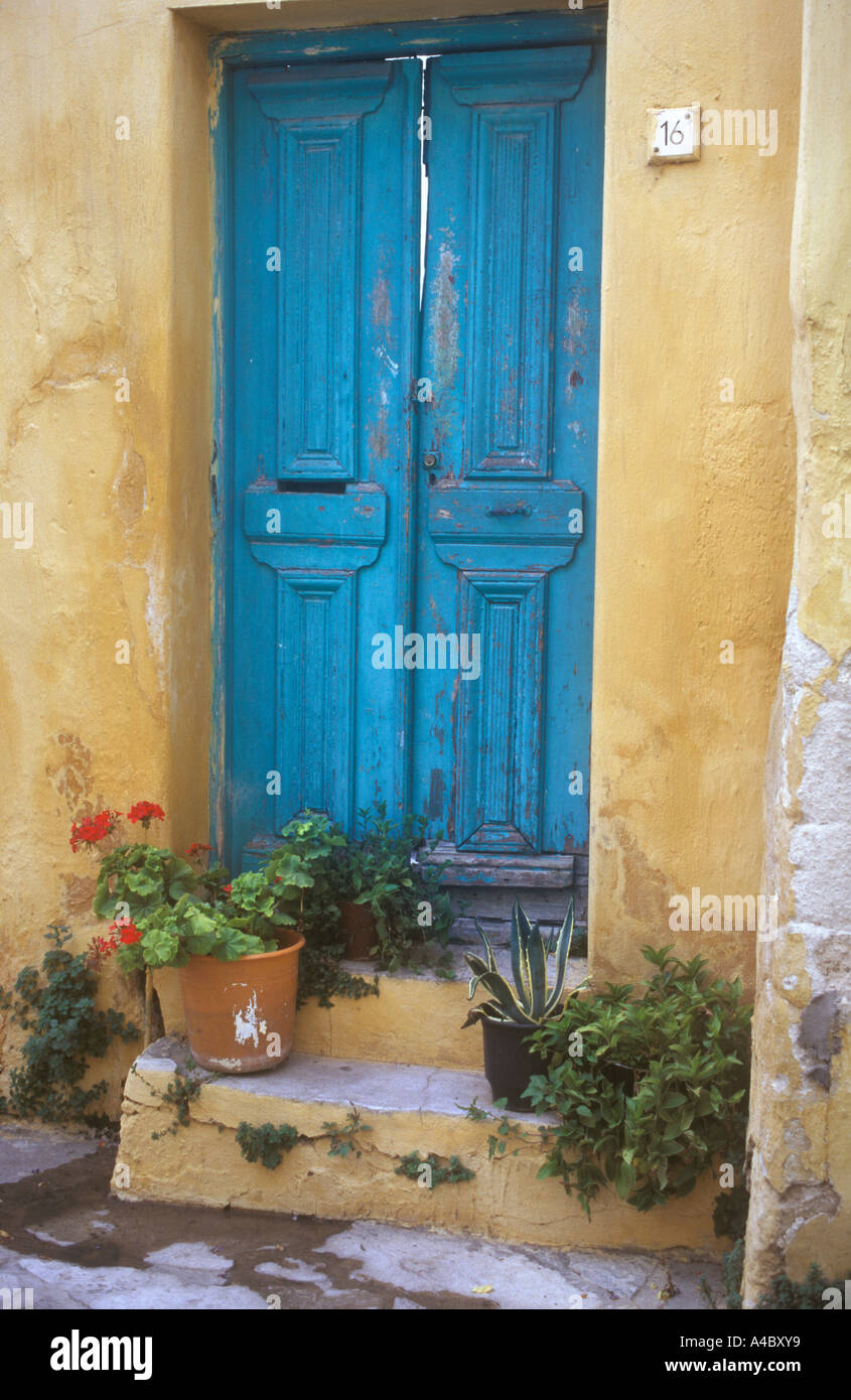 Porta blu con fiori di colore giallo e la parete sulla piccola strada laterale, Santorini Grecia Foto Stock