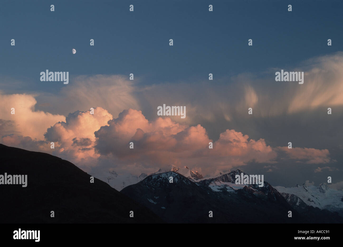 Luna crescente sopra le nuvole e le montagne illuminate dal sole di setting da Muottas Muragl, San Moritz Oberengadin in Svizzera Foto Stock
