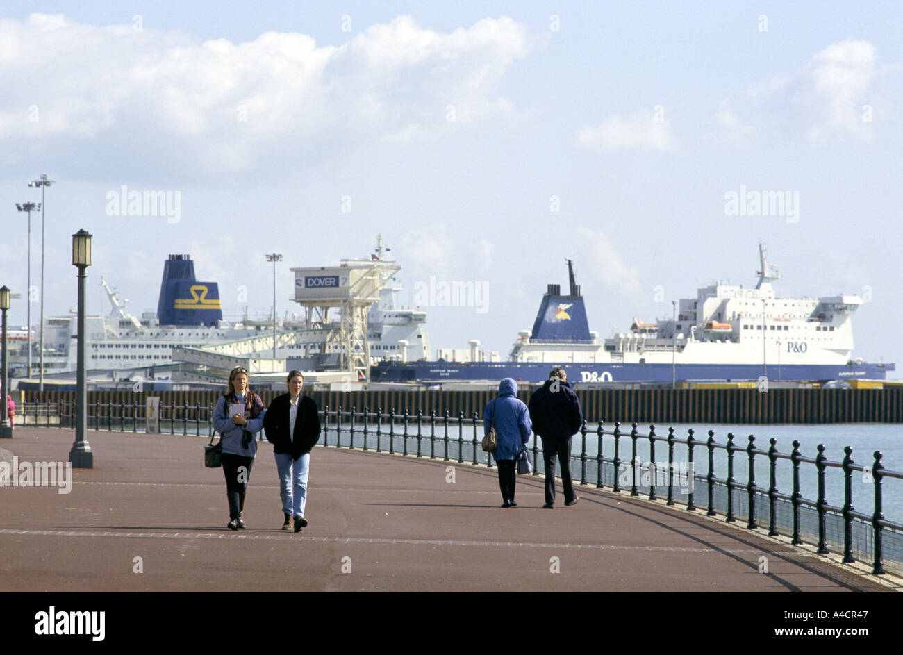 La gente a piedi lungo la passeggiata a Dover in Inghilterra del sud est della costa con le navi nella città di porto di traghetti in background Foto Stock