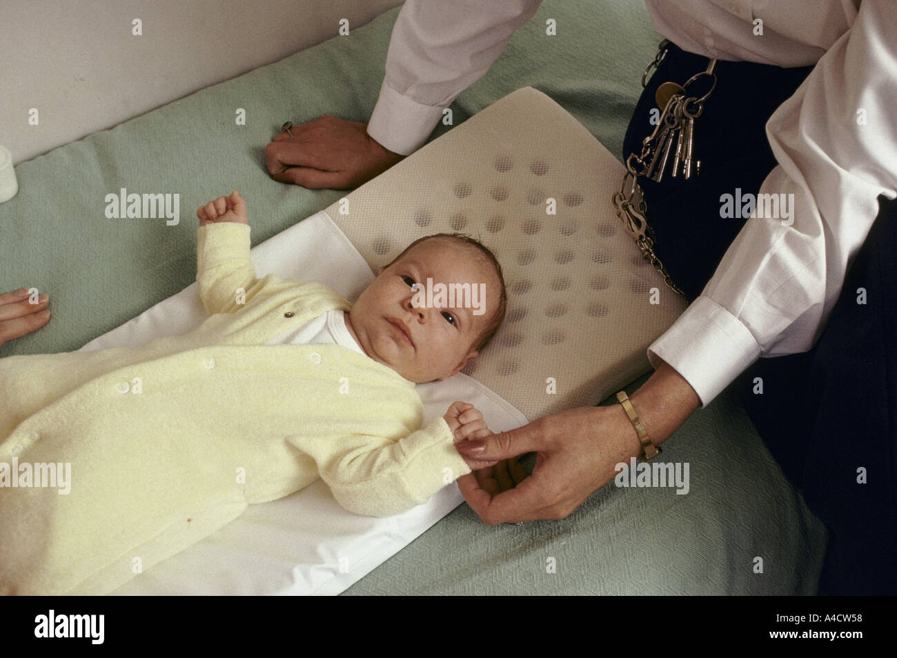 Un bambino giace su un letto, orologi da un funzionario delle carceri. Foto Stock