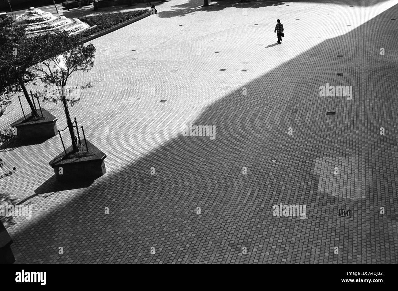 Un uomo che cammina attraverso uno spazio vuoto. Hong Kong, Repubblica Popolare di Cina, RAS DI HONG KONG Foto Stock