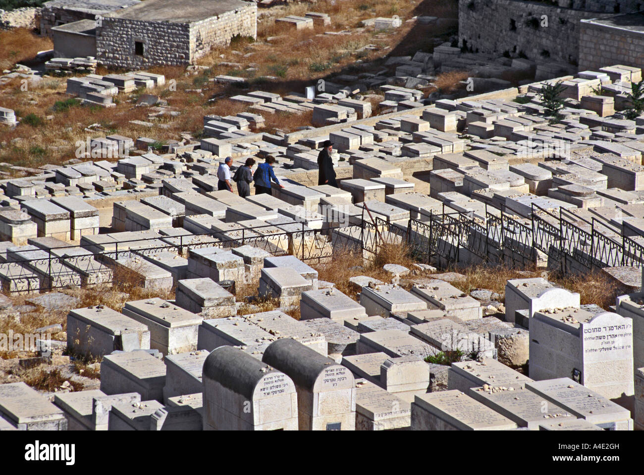 Quattro uomini visita tombe nel cimitero fuori le mura di Gerusalemme e la città vecchia di Israele Foto Stock