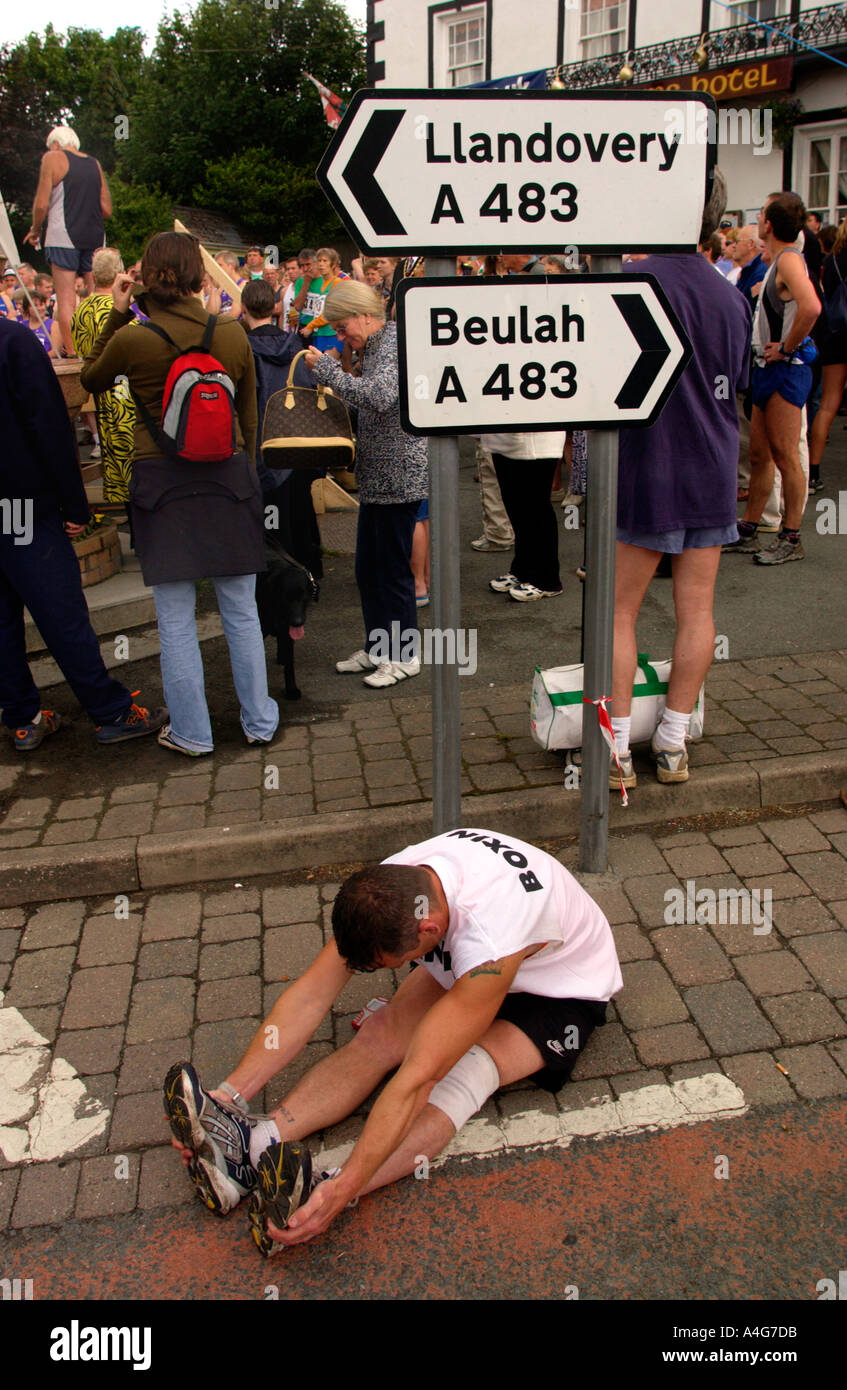 Concorrente limbering stretching prima l'uomo annuale v corsa di cavalli a Llanwrtyd Wells Powys Mid Wales UK Foto Stock