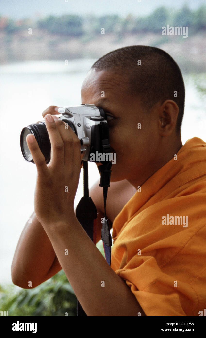 Un monaco novizio tenta di eseguire una fotocamera reflex in Pakse in Laos del sud Foto Stock