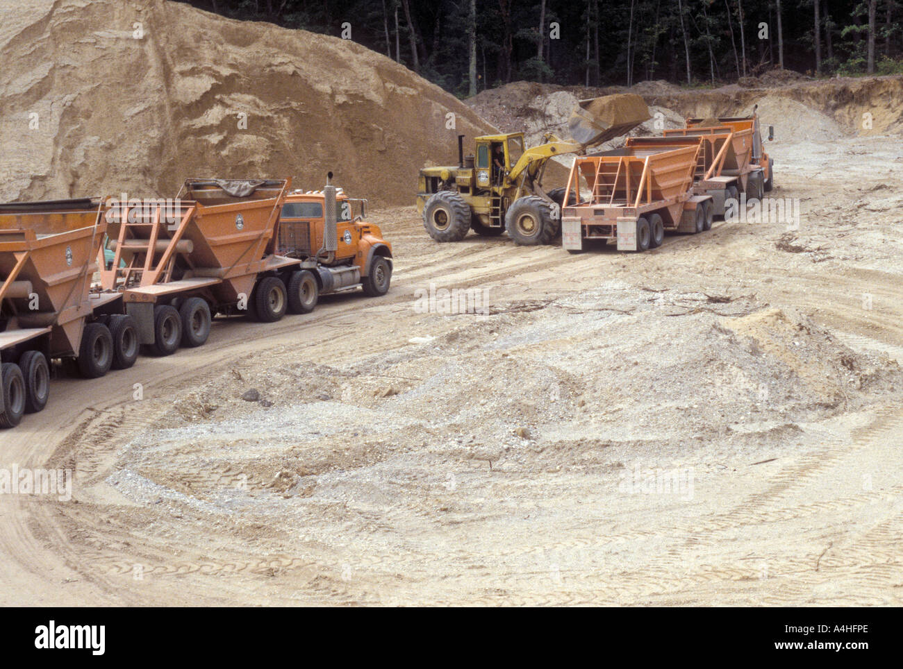 Caricatore frontale carichi ghiaia nei carrelli nella fossa di ghiaia Foto Stock