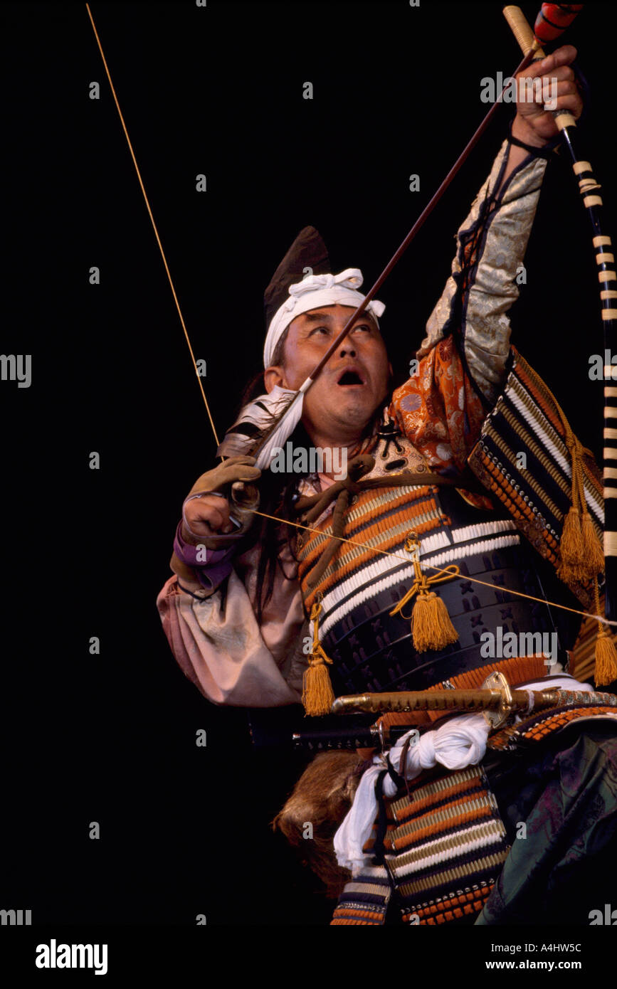 Un Guerriero giapponese attore tiro arco e frecce nel tiro con l'arco fase rituale prestazioni e indossando il costume tradizionale dal Giappone Foto Stock