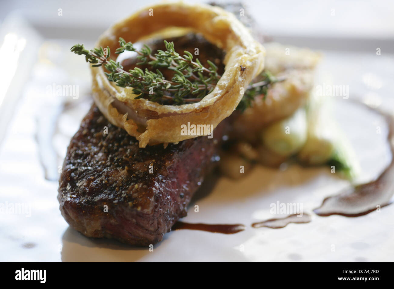 Bistecca di New York con anello di cipolla, erbe aromatiche, ortaggi e demi-glace Foto Stock