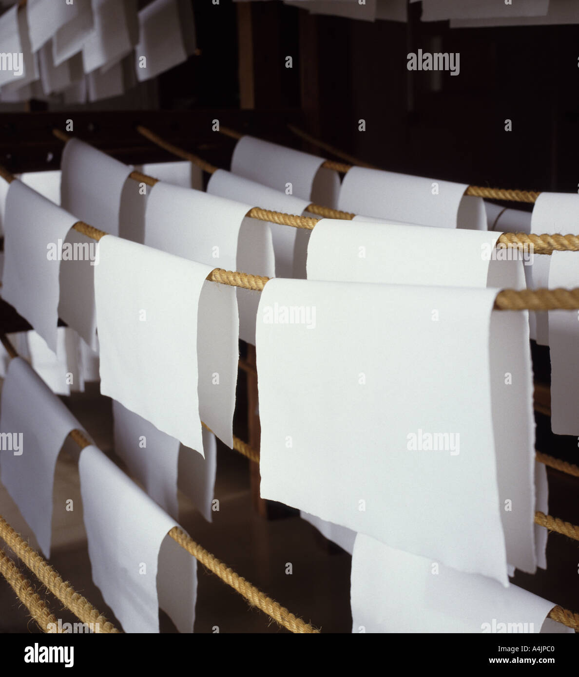 Fogli di carta fatta a mano appesa ad asciugare a cavallo delle corde in un loft di essiccazione Foto Stock