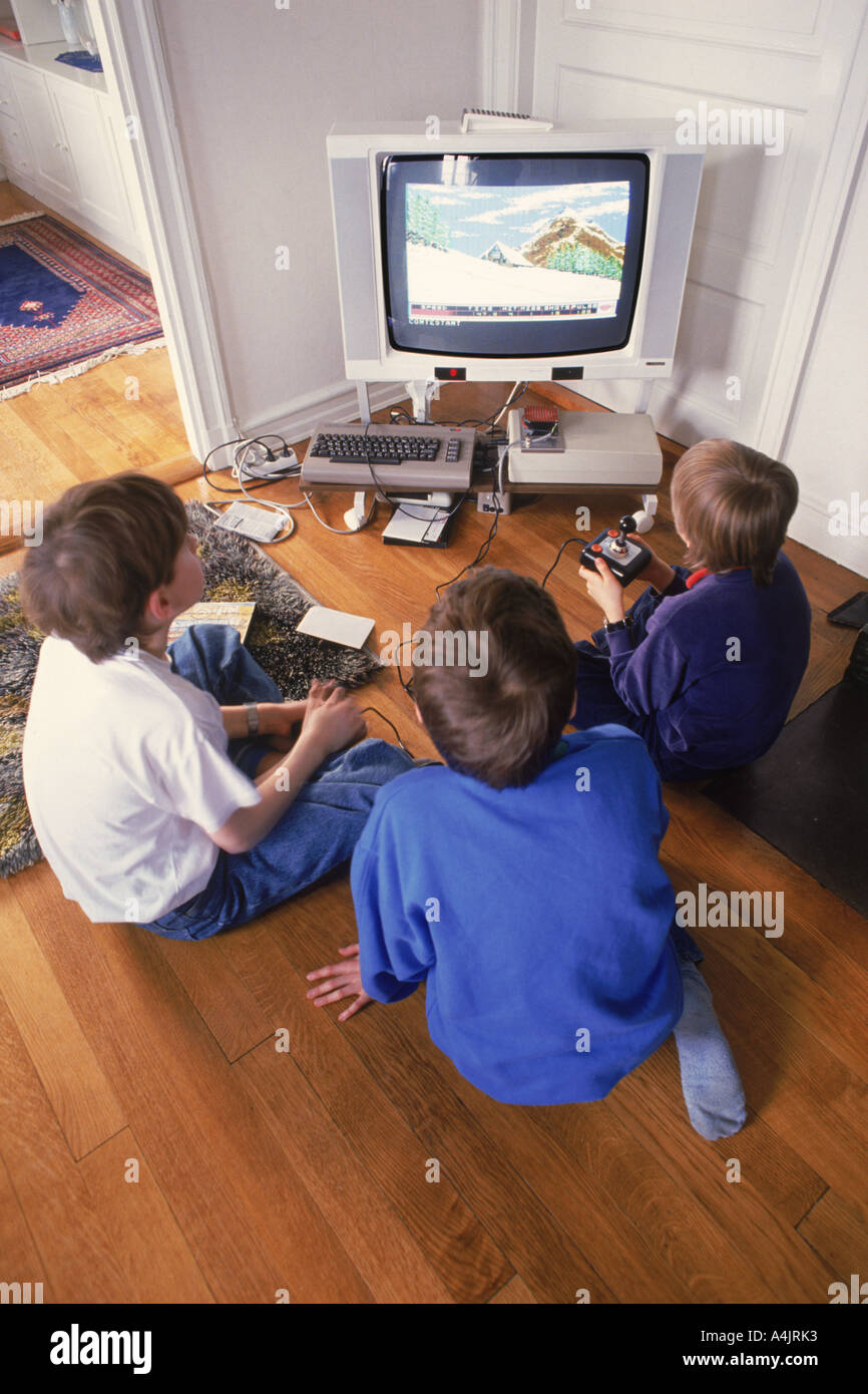 Tre ragazzi sul pavimento con il televisore di casa per la riproduzione di video giochi Foto Stock