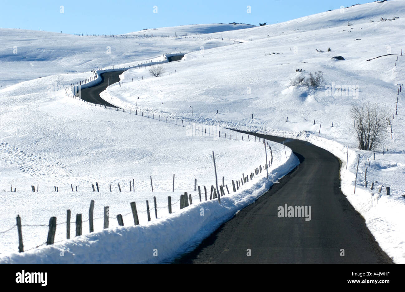 La guida attraverso un paesaggio innevato su un avvolgimento strada rurale in inverno Foto Stock