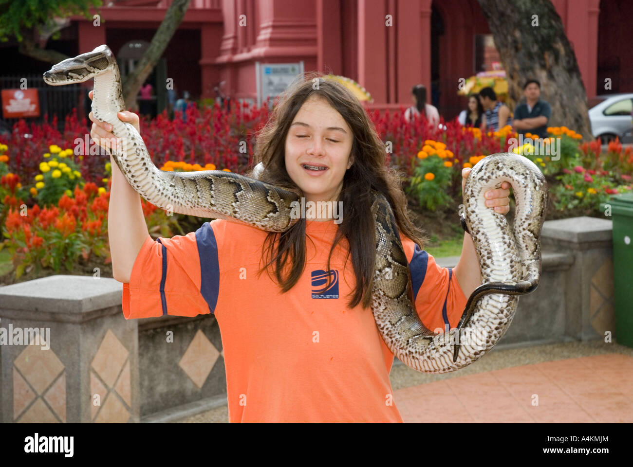 Un capelli lunghi boy pone per s foto tenendo un python in Malacca Malaysia Foto Stock