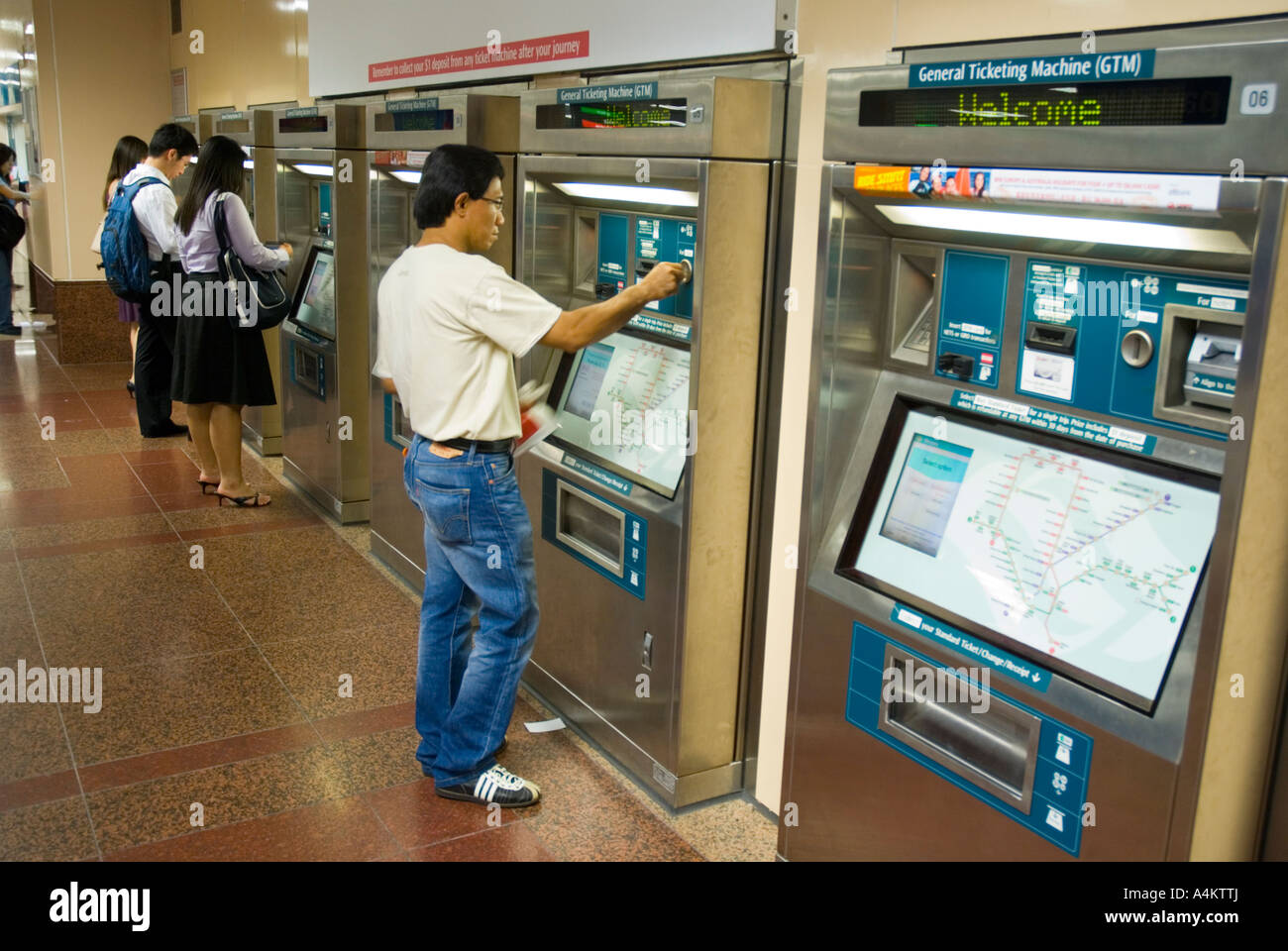 I passeggeri che utilizzano le biglietterie automatiche per Singapore urbana sistema di treno Foto Stock