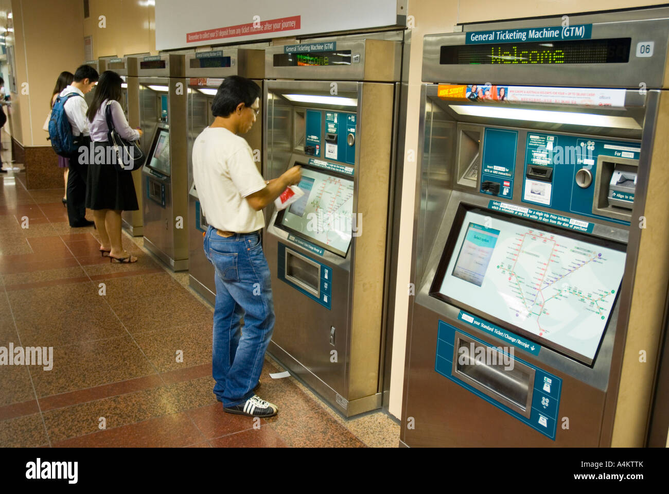 I passeggeri che utilizzano le biglietterie automatiche per Singapore urbana sistema di treno Foto Stock