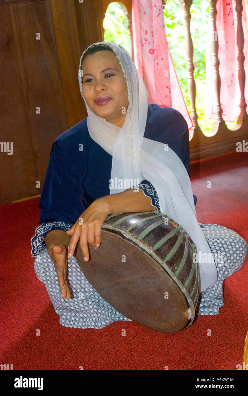 Un Malay donna musulmana di cantare e suonare un tamburo tradizionale al Sarawak centro culturale Foto Stock