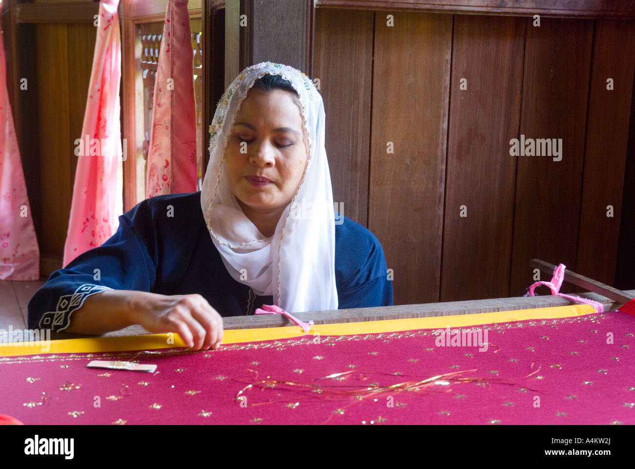 Un Malay donna musulmana funzionante a raffinati ricami in oro filato al Sarawak centro culturale vicino a Kuching Foto Stock