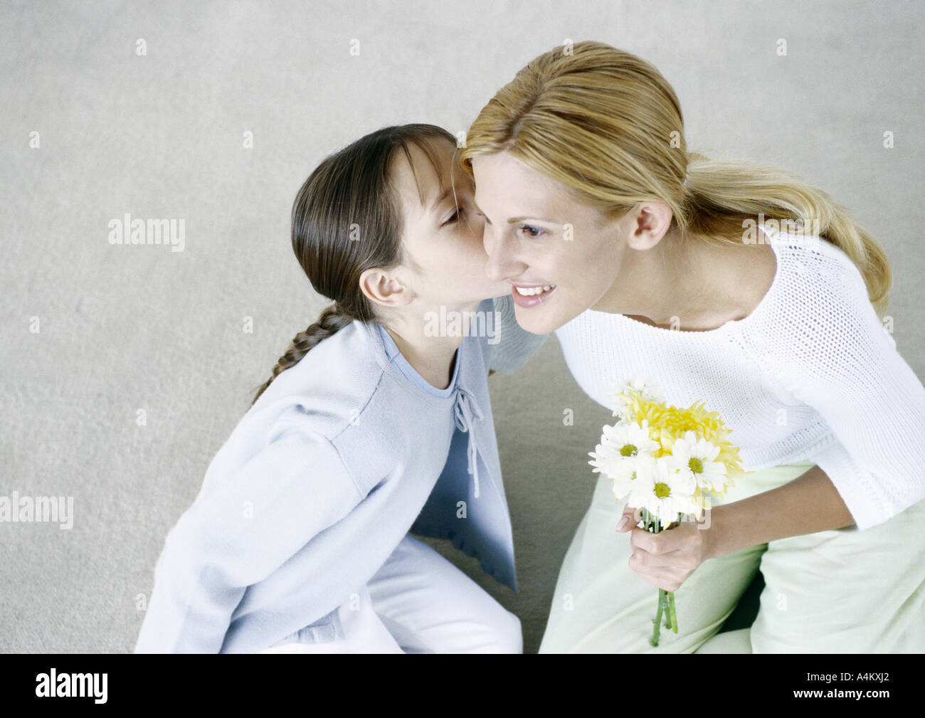 Donna che mantiene bouquet di fiori, ragazza baciare sulla guancia Foto Stock