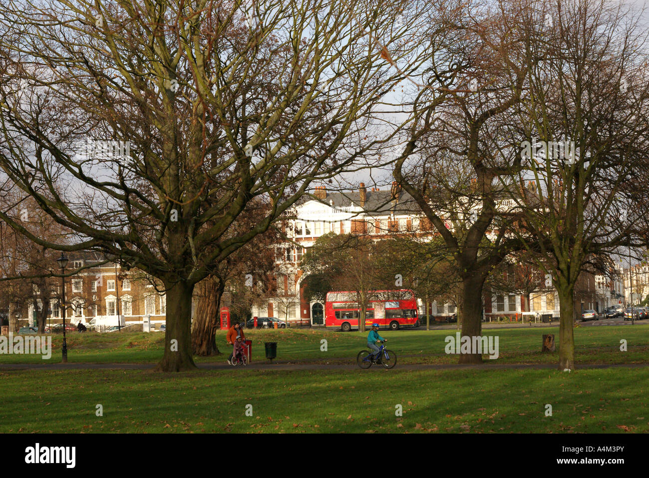 I bambini che imparano il ciclismo e godendo di autunno lasciare e alberi in clapham common a Londra England Regno Unito Foto Stock