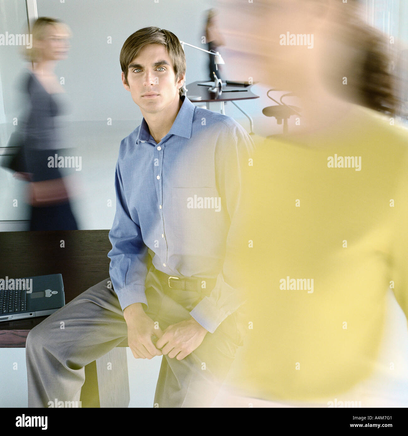 Uomo seduto sul bordo della scrivania in ufficio occupato Foto Stock