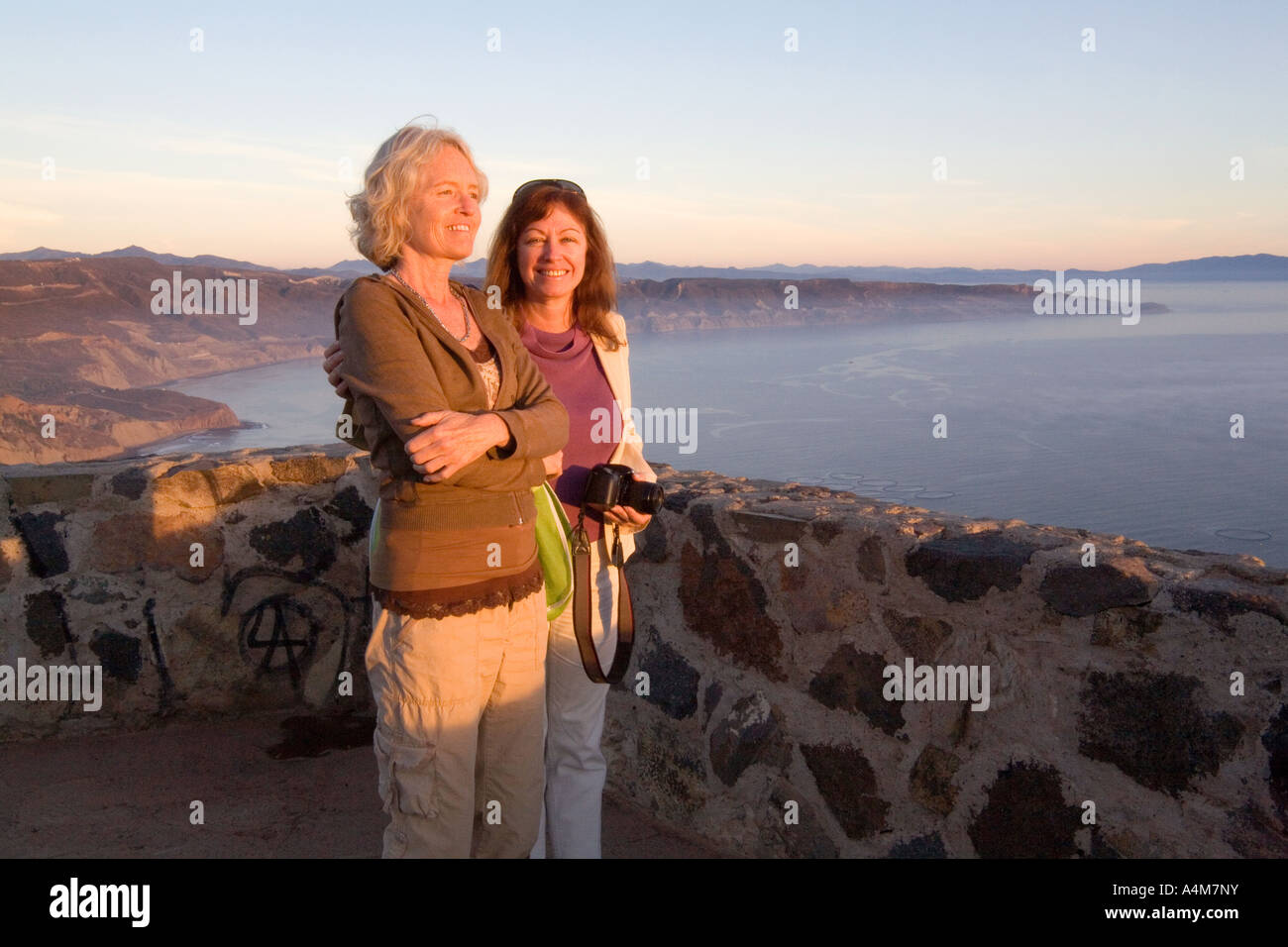 Due donne su un piedistallo di vacanza insieme e ammirare un tramonto d'estate. Foto Stock