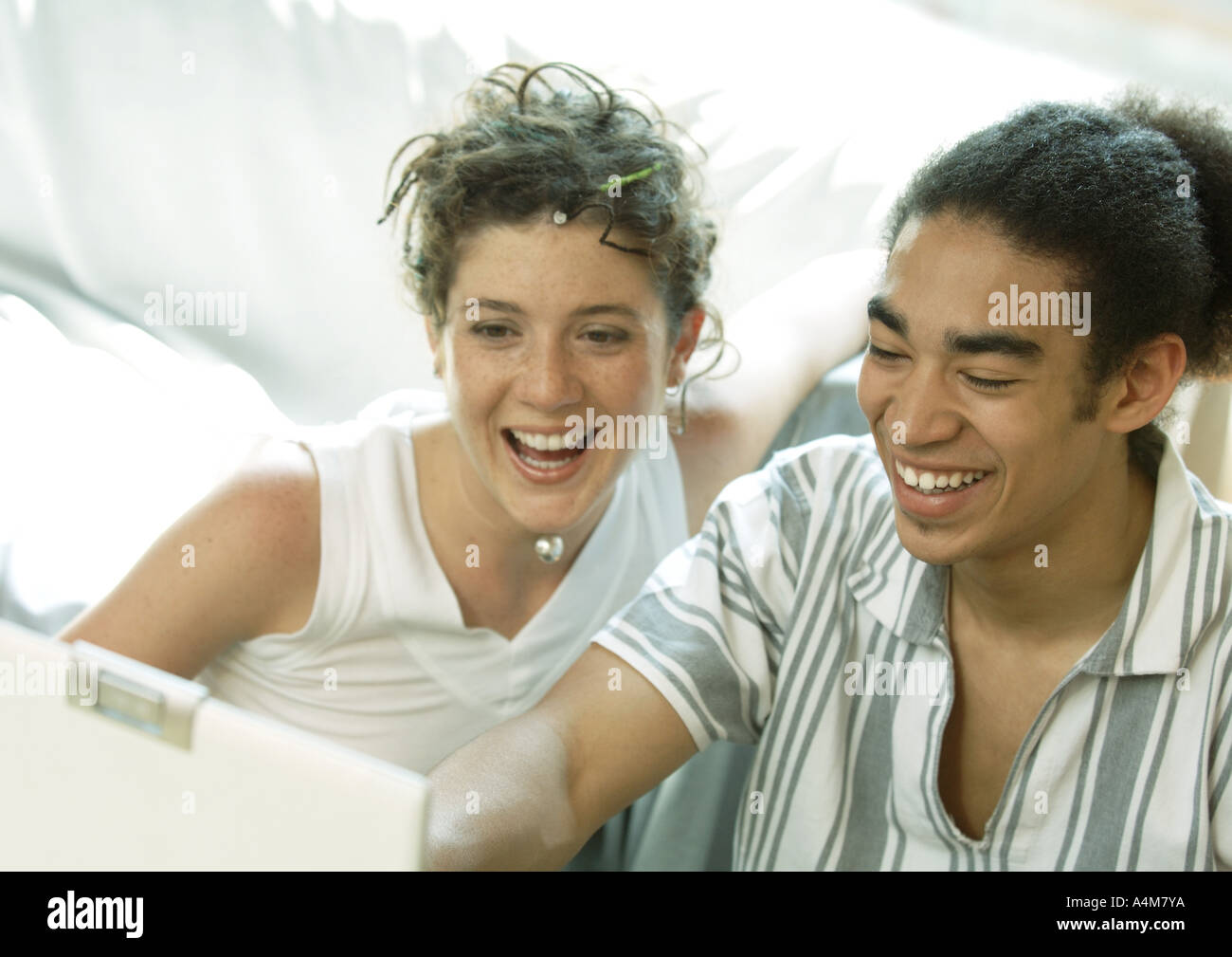 Coppia giovane guardando laptop, sorridente Foto Stock