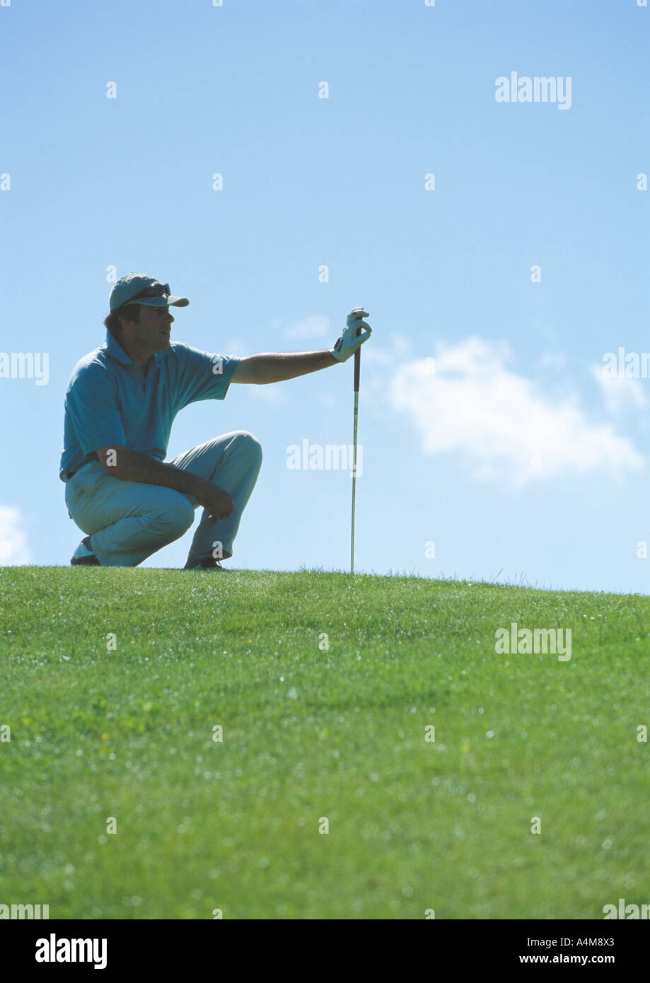 Il Golfer squatting su verde Foto Stock