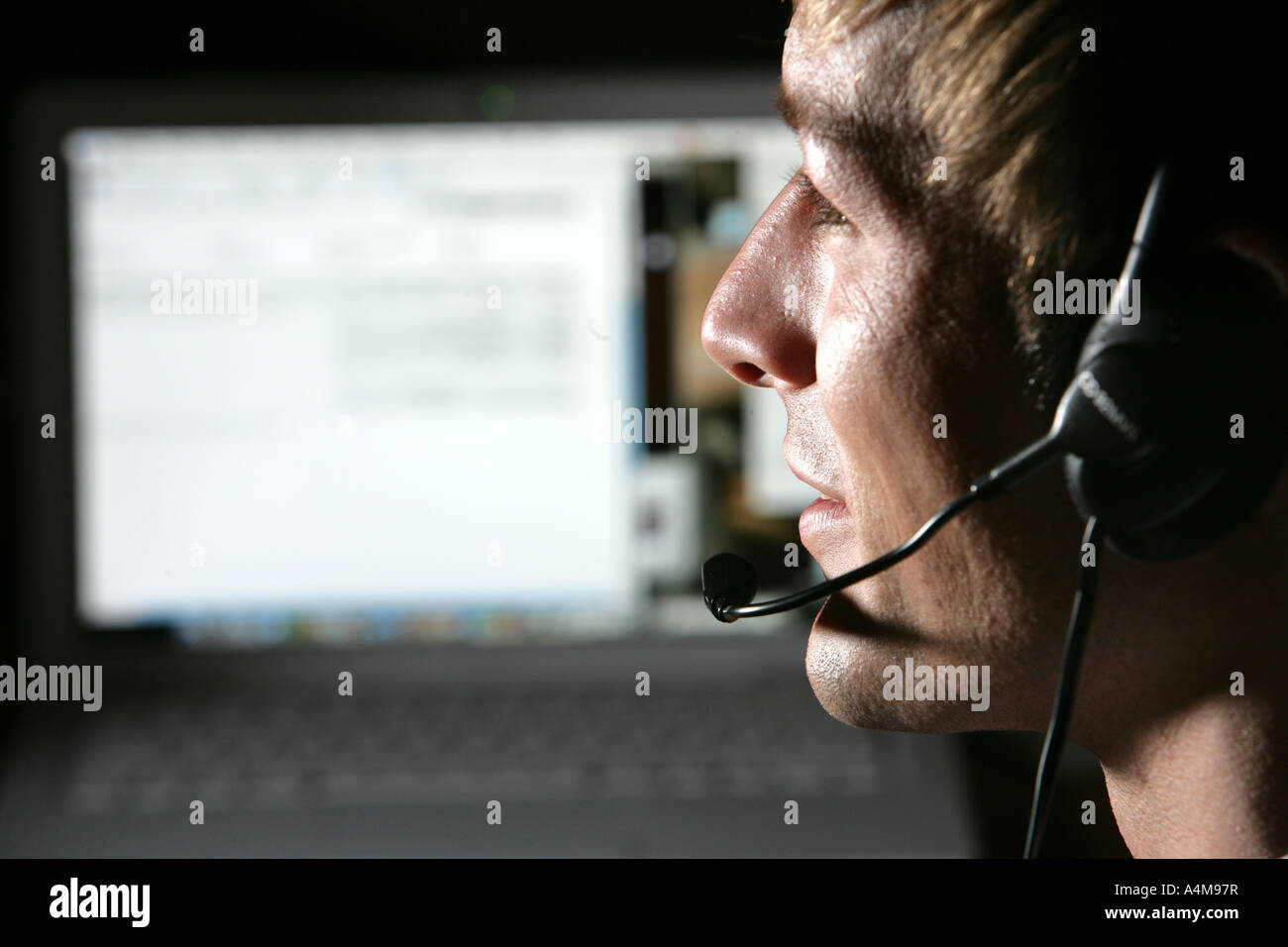 Persona di sesso maschile si sta parlando al telefono e Internet, Voice over IP, usando un auricolare con microfono, nella parte anteriore del monitor di un computer. Foto Stock