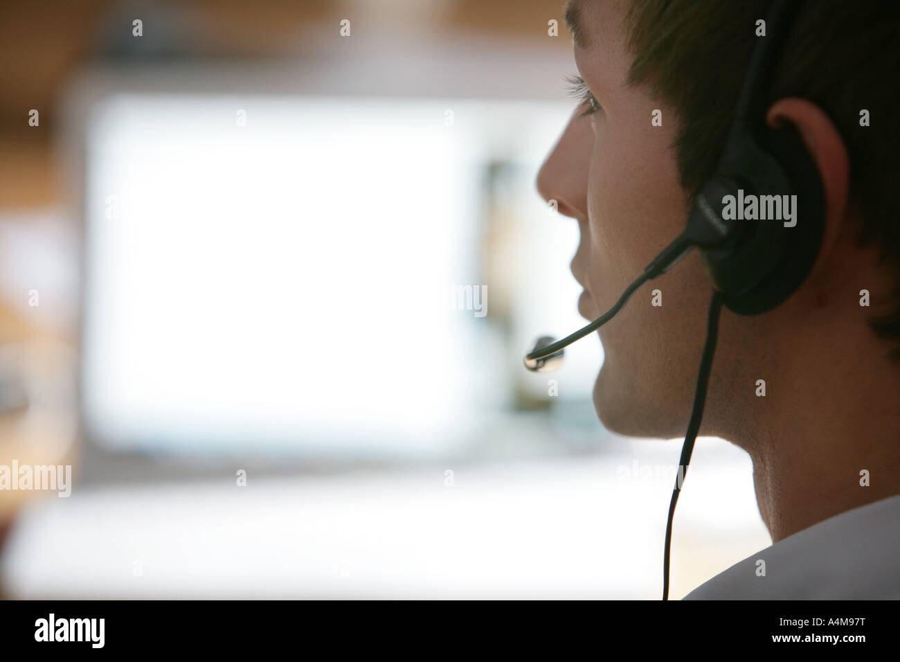 Persona di sesso maschile si sta parlando al telefono e Internet, Voice over IP, usando un auricolare con microfono, nella parte anteriore del monitor di un computer. Foto Stock