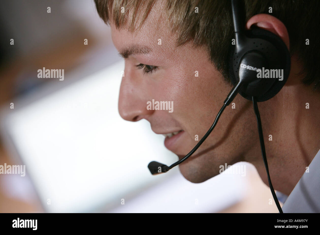 Persona di sesso maschile si sta parlando al telefono e Internet, Voice over IP, usando un auricolare con microfono, nella parte anteriore del monitor di un computer. Foto Stock