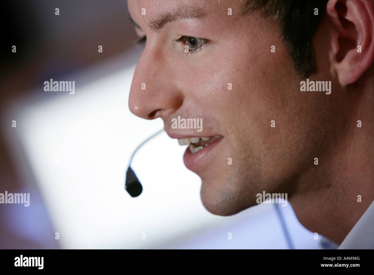 Persona di sesso maschile si sta parlando al telefono e Internet, Voice over IP, usando un auricolare con microfono, nella parte anteriore del monitor di un computer. Foto Stock