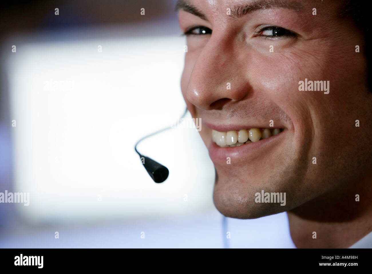Persona di sesso maschile si sta parlando al telefono e Internet, Voice over IP, usando un auricolare con microfono, nella parte anteriore del monitor di un computer. Foto Stock