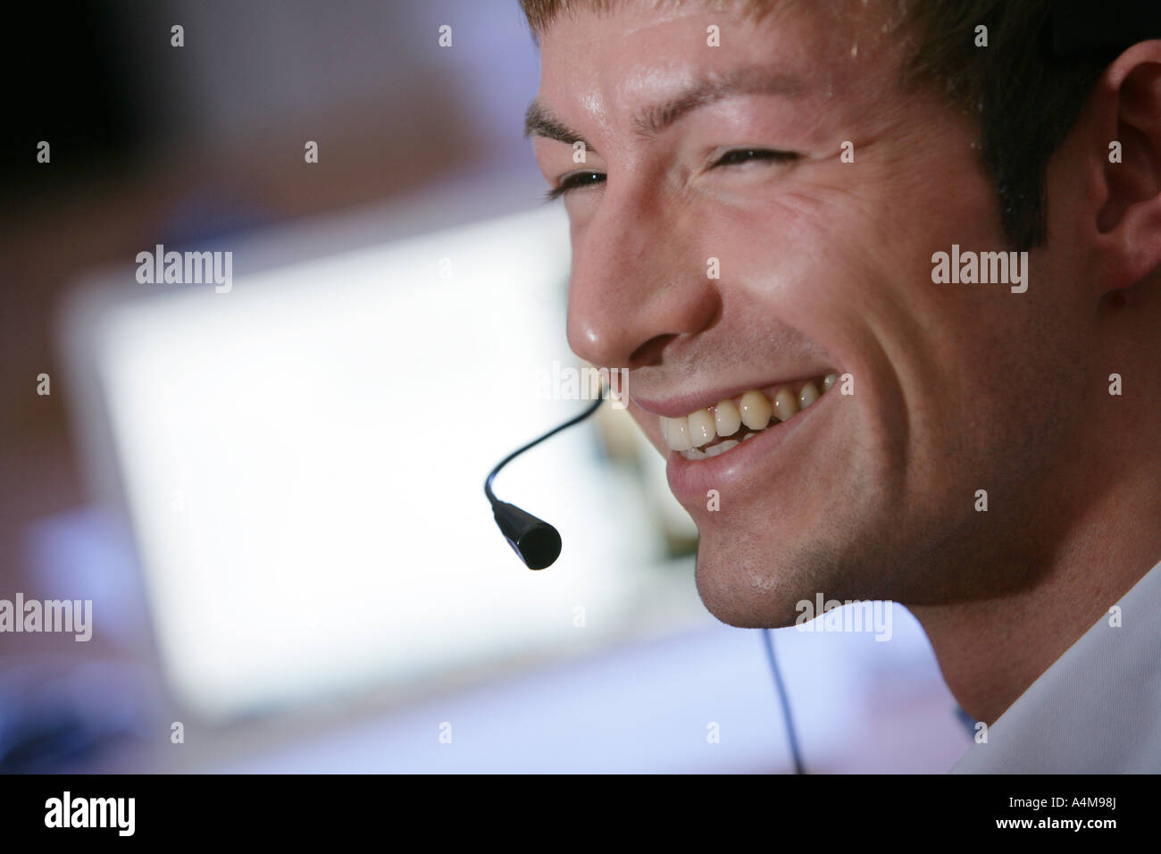 Persona di sesso maschile si sta parlando al telefono e Internet, Voice over IP, usando un auricolare con microfono, nella parte anteriore del monitor di un computer. Foto Stock