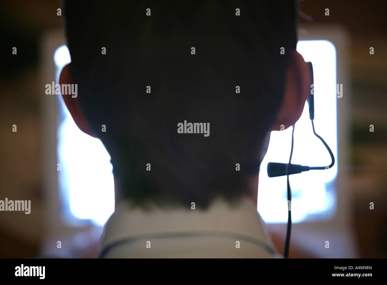 Persona di sesso maschile si sta parlando al telefono e Internet, Voice over IP, usando un auricolare con microfono, nella parte anteriore del monitor di un computer. Foto Stock
