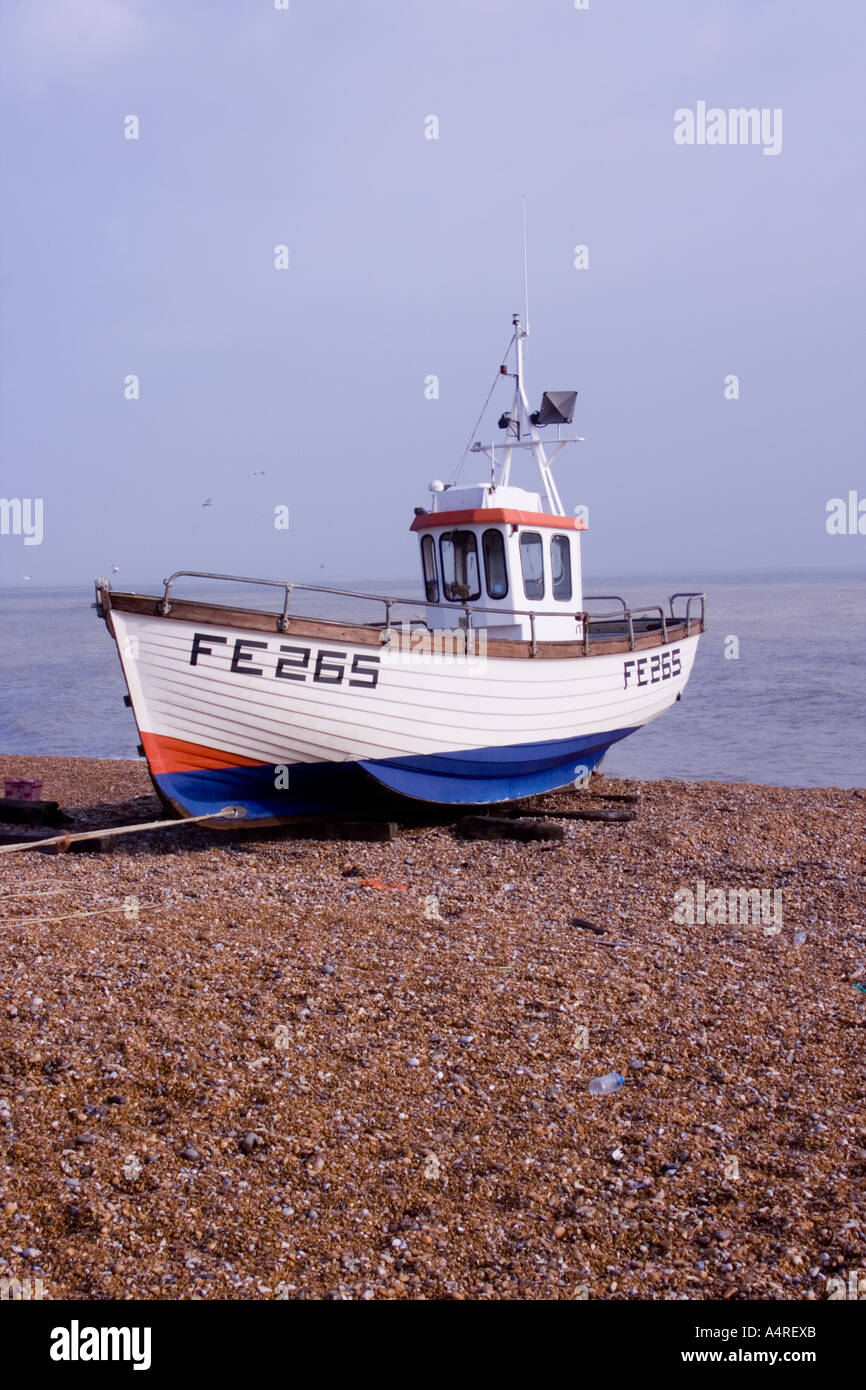 Piccolo rosso, bianco e blu barca da pesca sulla spiaggia di Dungeness in verticale Kent Foto Stock