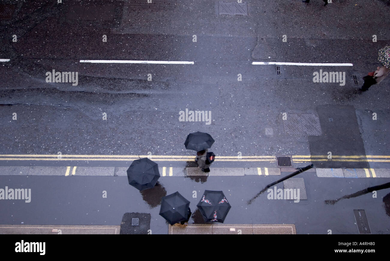 Shelter pedoni a piedi sotto la pioggia con ombrelli sul marciapiede in London Street Foto Stock