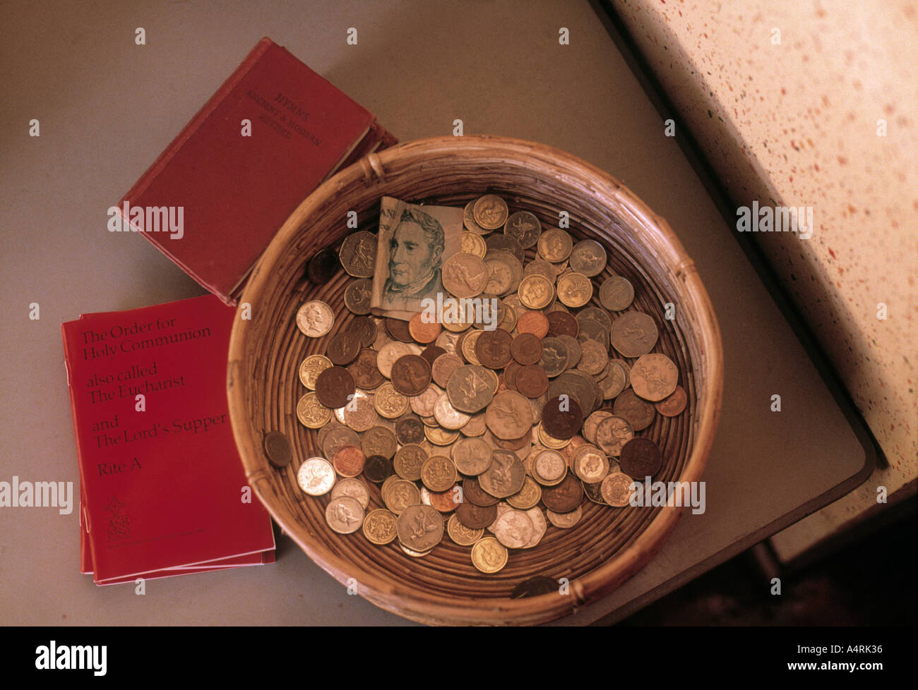 La piastra di raccolta piena di monete e l'ordine della santa comunione la Chiesa libri Foto Stock