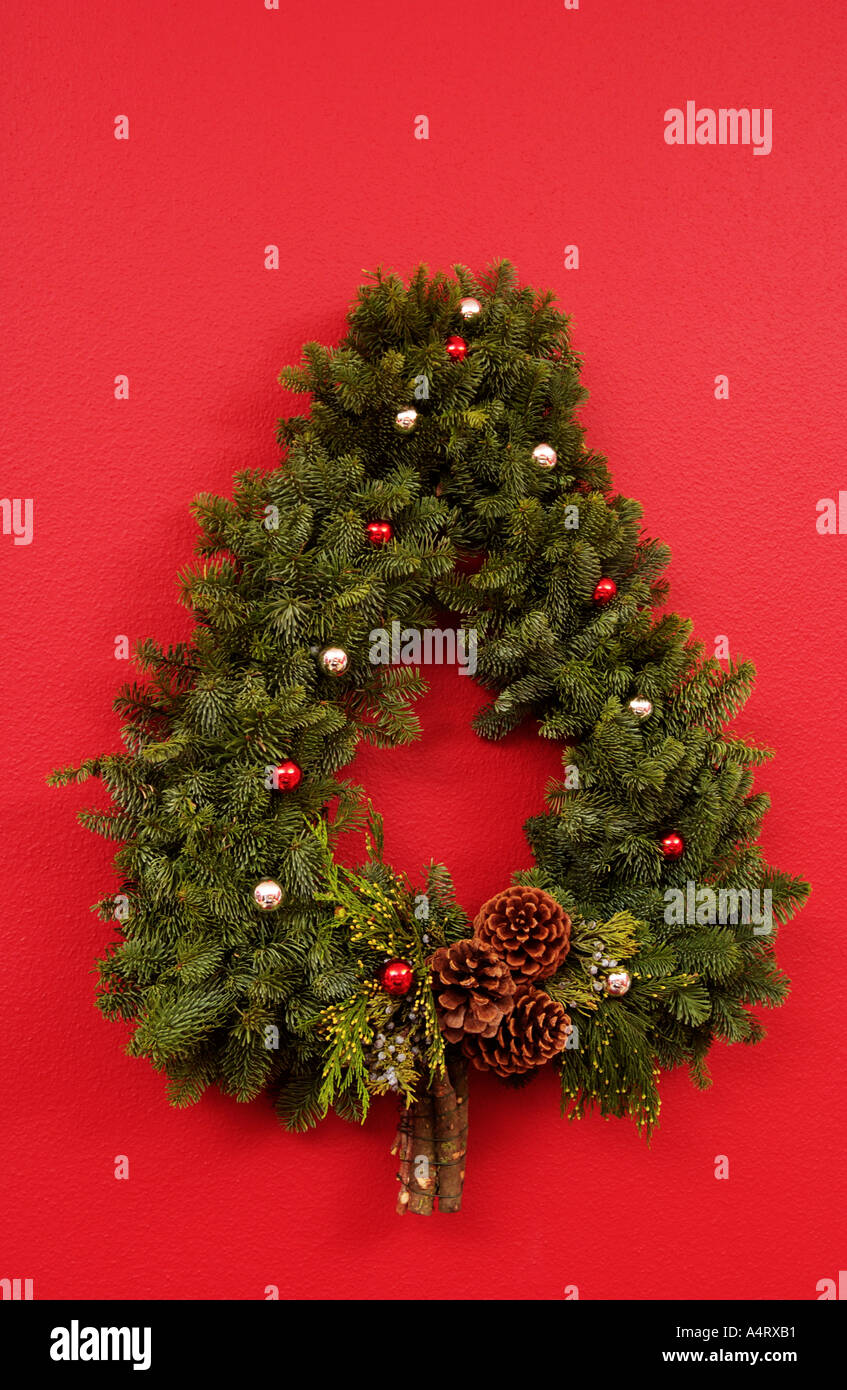 Albero di Natale a forma di corona sulla parete rossa Foto Stock