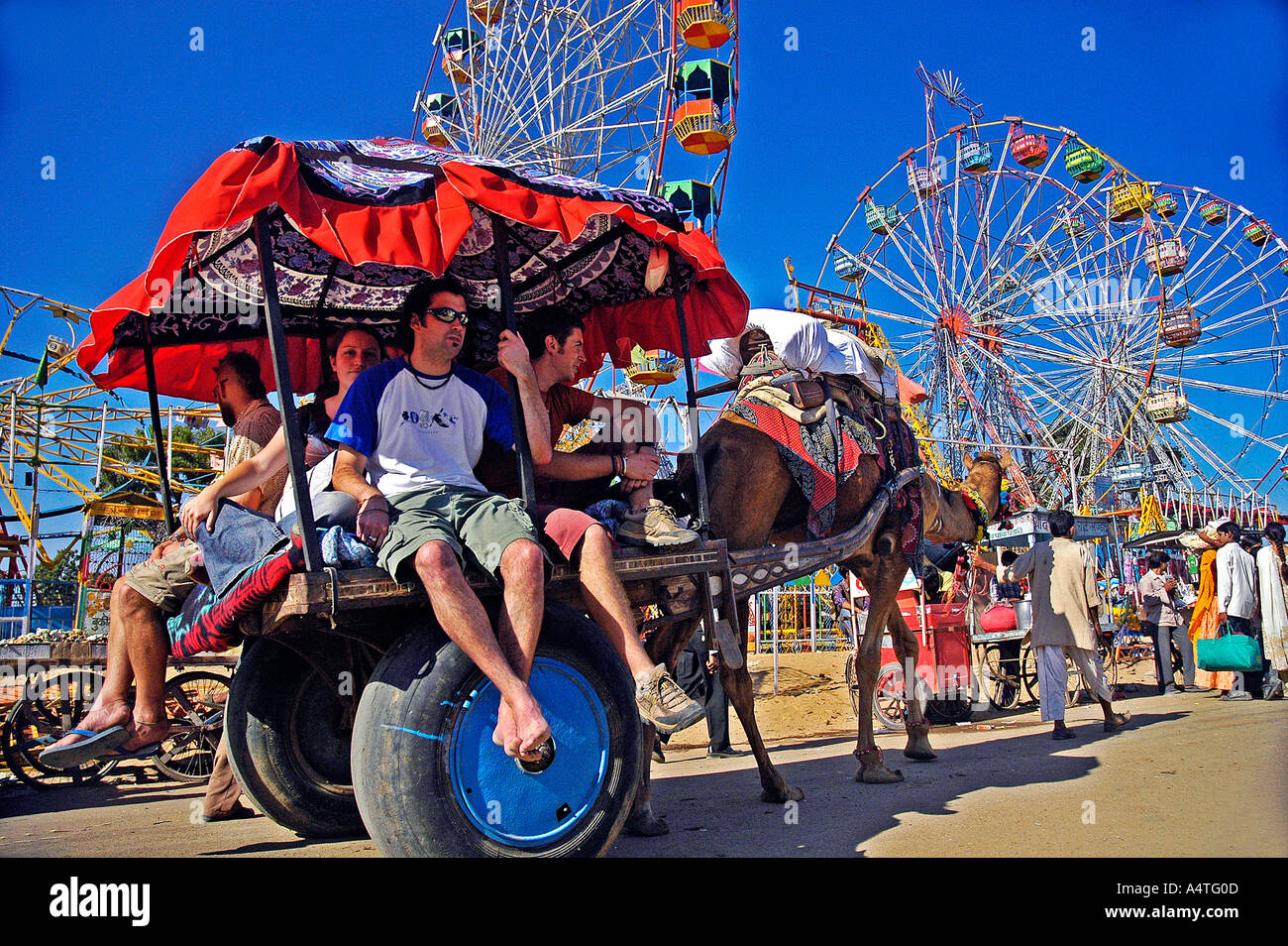 I turisti a dorso di cammello carrello fiera di Pushkar Rajasthan in India Foto Stock