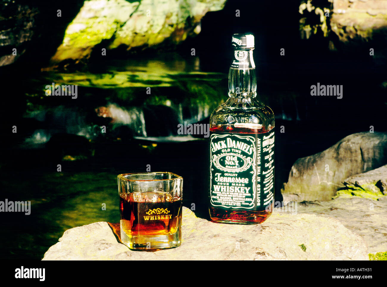 Bottiglia e bicchiere di Jack Daniels whiskey accanto alla fonte di acqua corrente a molla nella distilleria di Lynchburg, Tennessee, Stati Uniti d'America Foto Stock