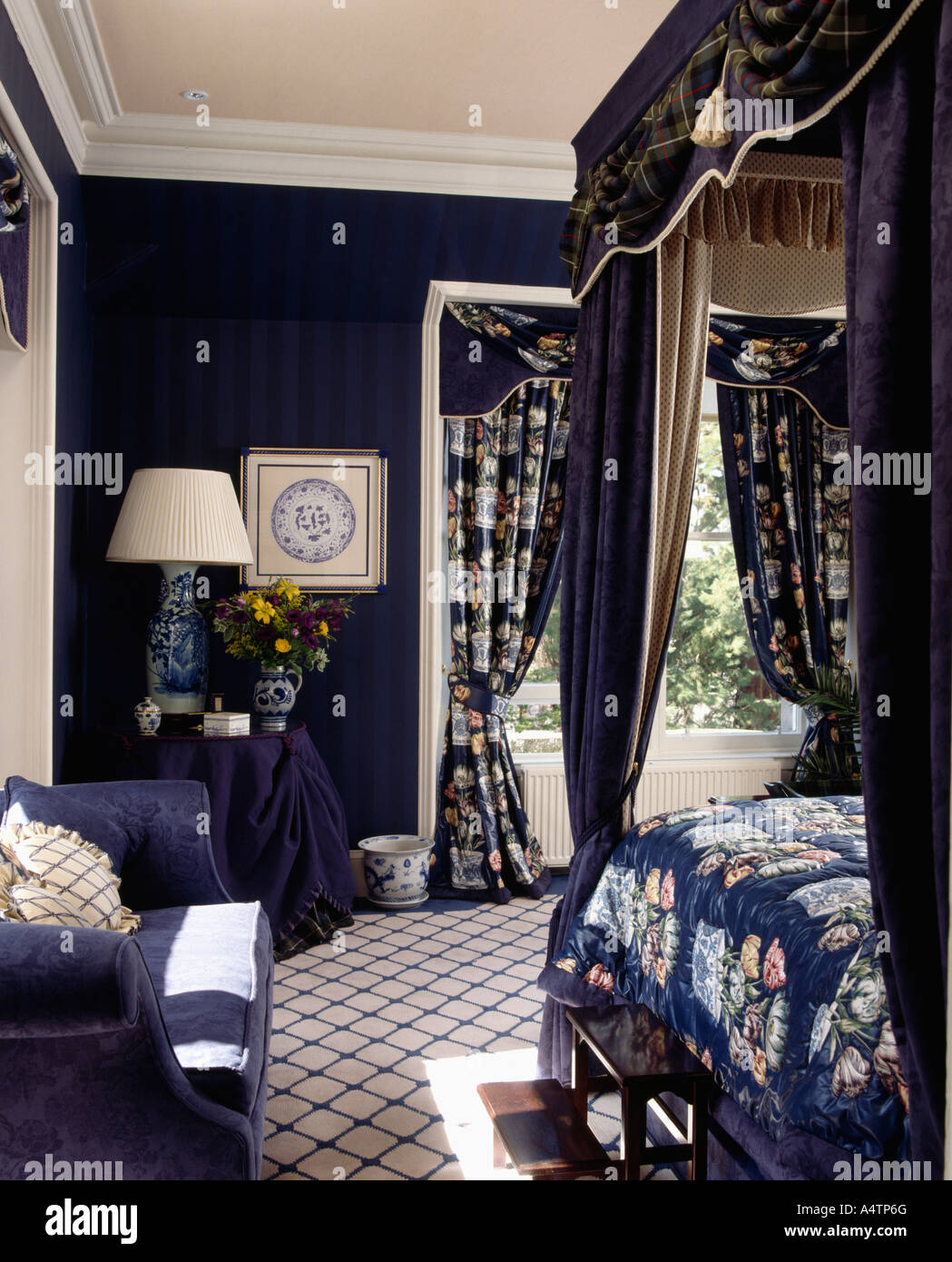 Camera da letto con moquette a motivi geometrici e blu scuro e pareti  fourposter bed con fantasia blu biancheria e tende Foto stock - Alamy