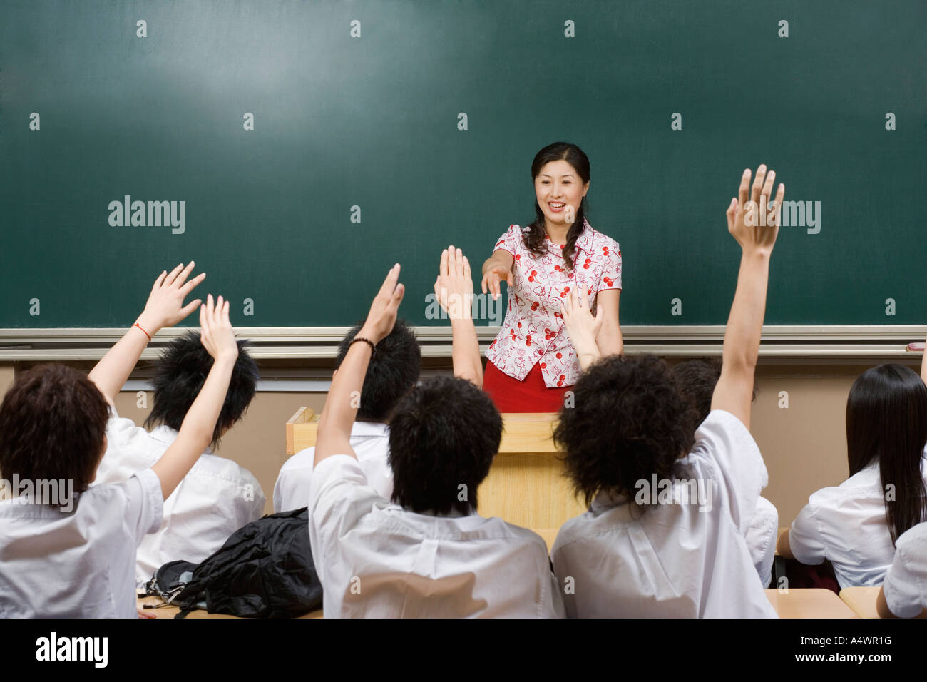 Gli studenti alzando le mani in classe Foto Stock