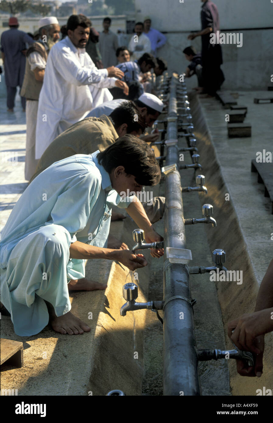 Gli uomini musulmani si esibiscono nel wudu, o si lavano prima di pregare in una moschea del Pakistan Foto Stock